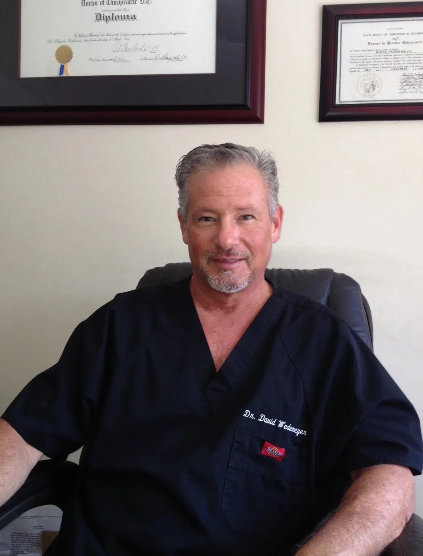 Founder David Wedemeyer seated in clinical attire in front of framed credentials.